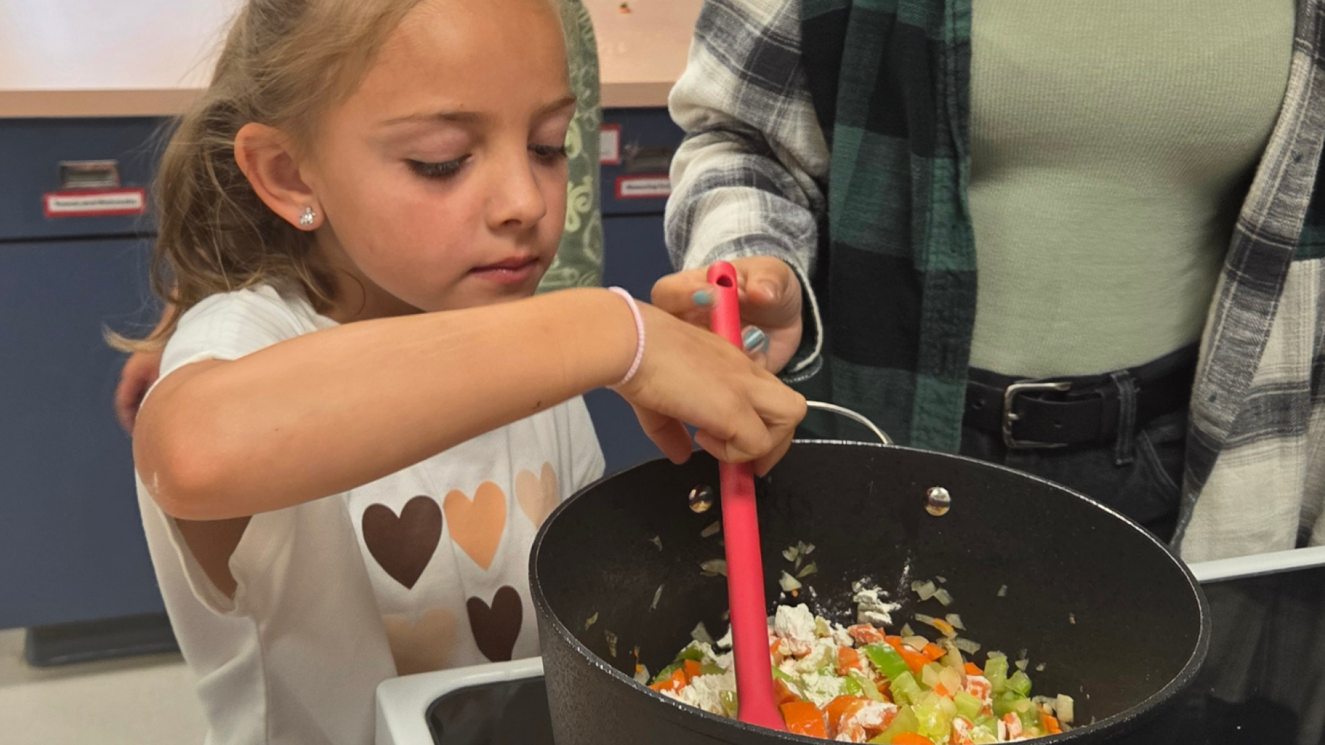 A child learning how to cook with supervision.
