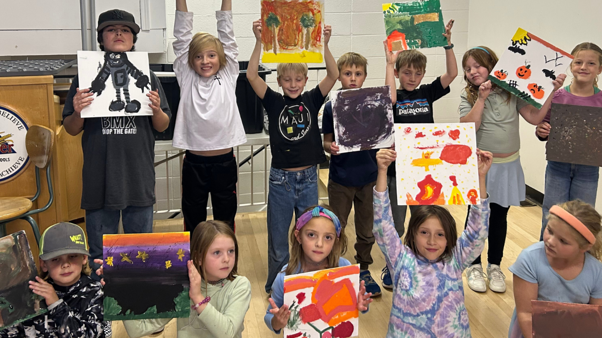 A group of children showing off their artwork at Creative Camp.