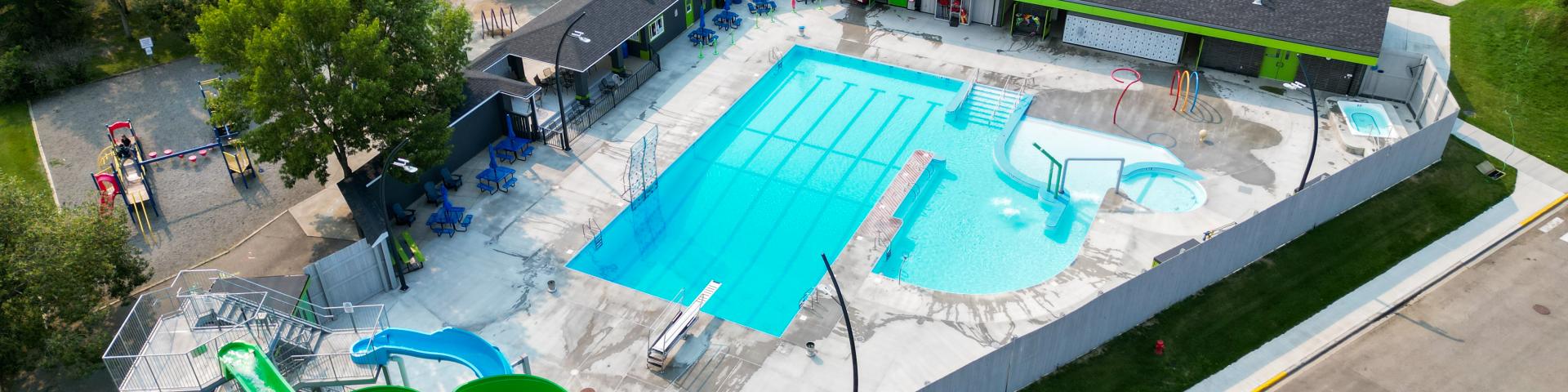 Birds-eye-view of the Vulcan Lion's Community pool, featuring 2 waterslides, large pool, spray park and hot tub.