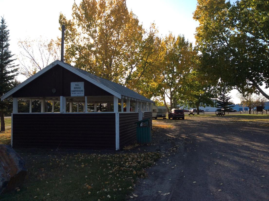 Vulcan Municipal Campground. There is a wooden gazebo in the foreground and some cars parked in the background.