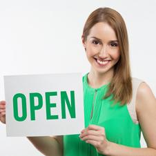 Lady holding on a sign that reads "Open" in green text.